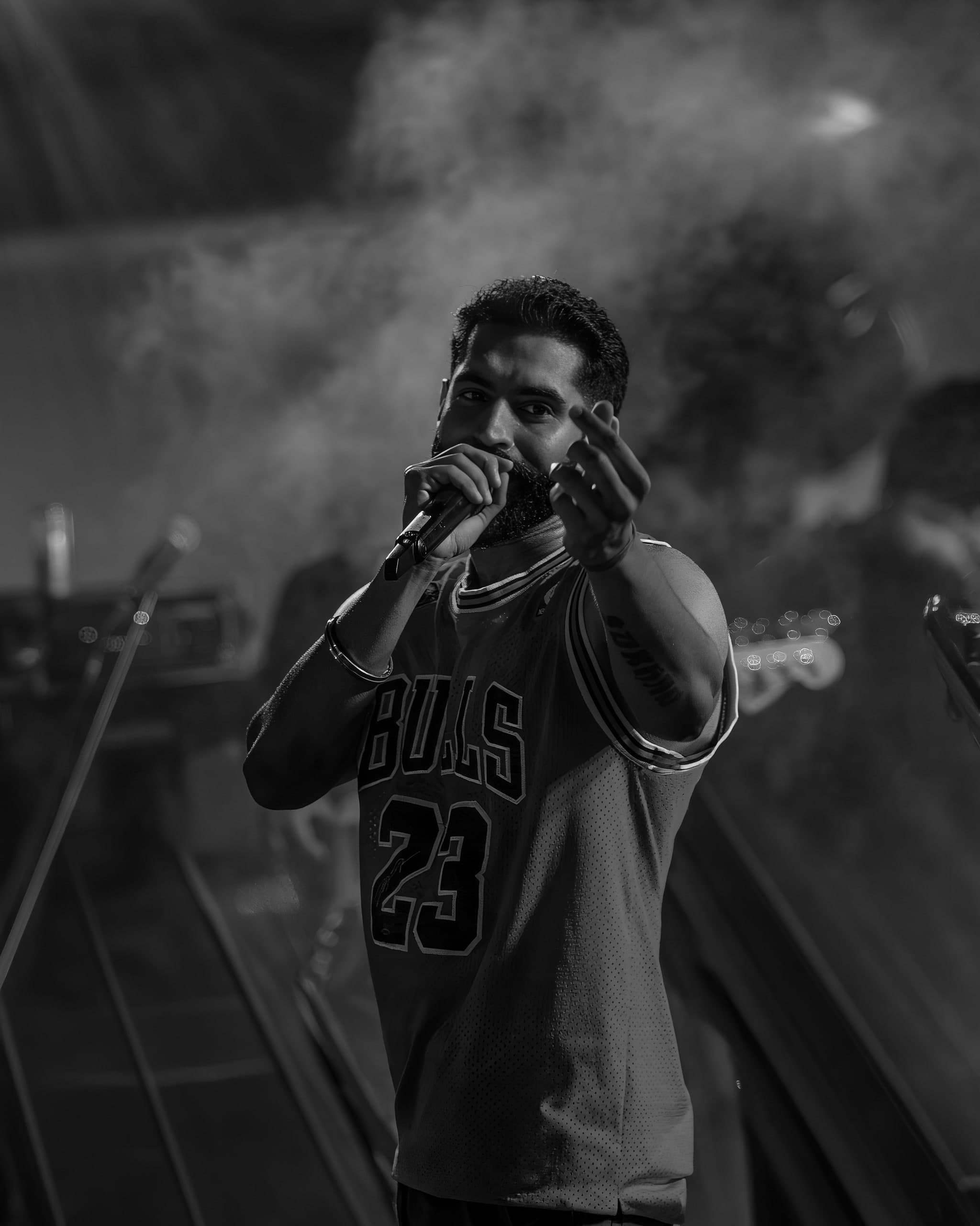 Black and white — performer at the mic with the crowd below the stage