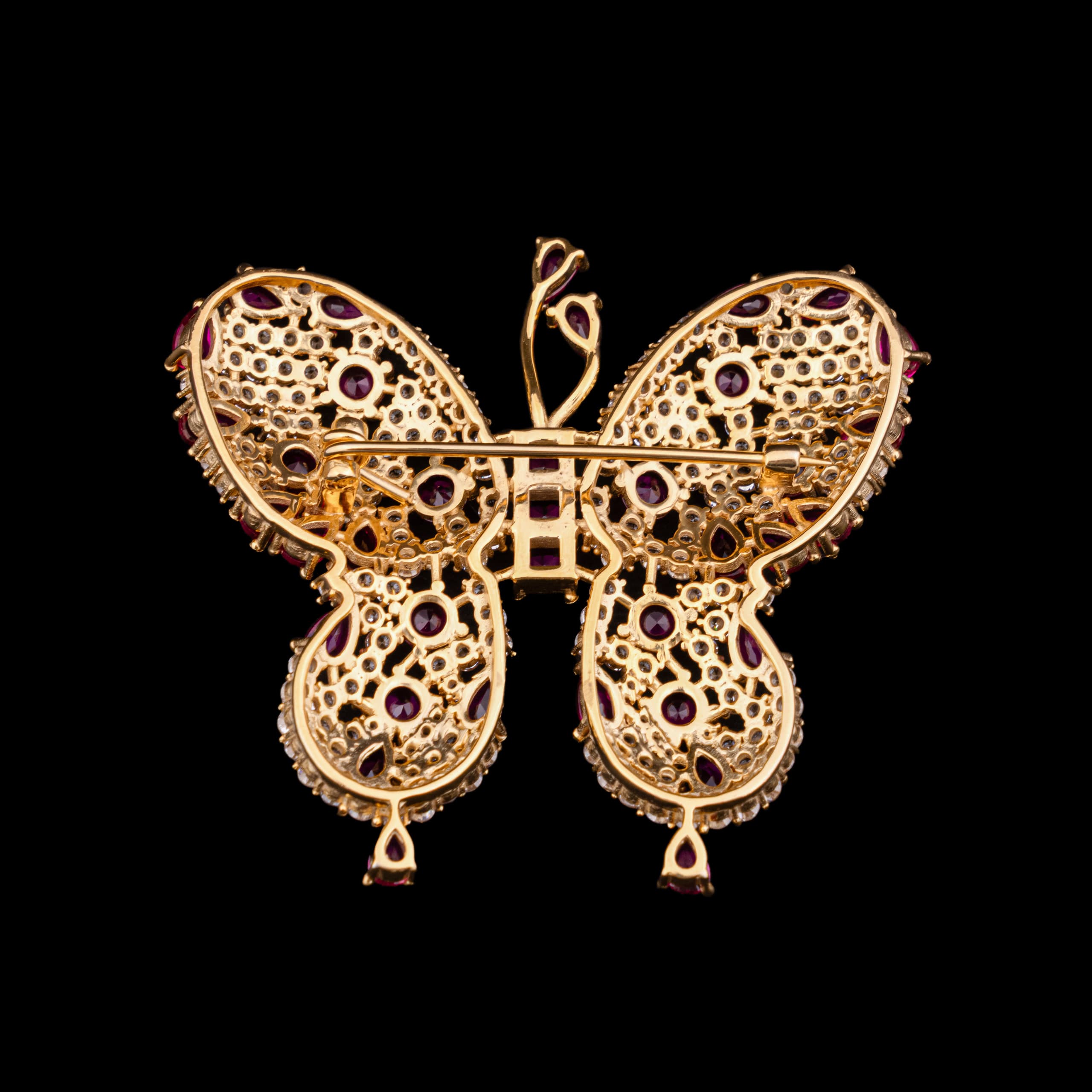 The butterfly brooch from behind: open gold honeycomb, the pin bar laid across the wings