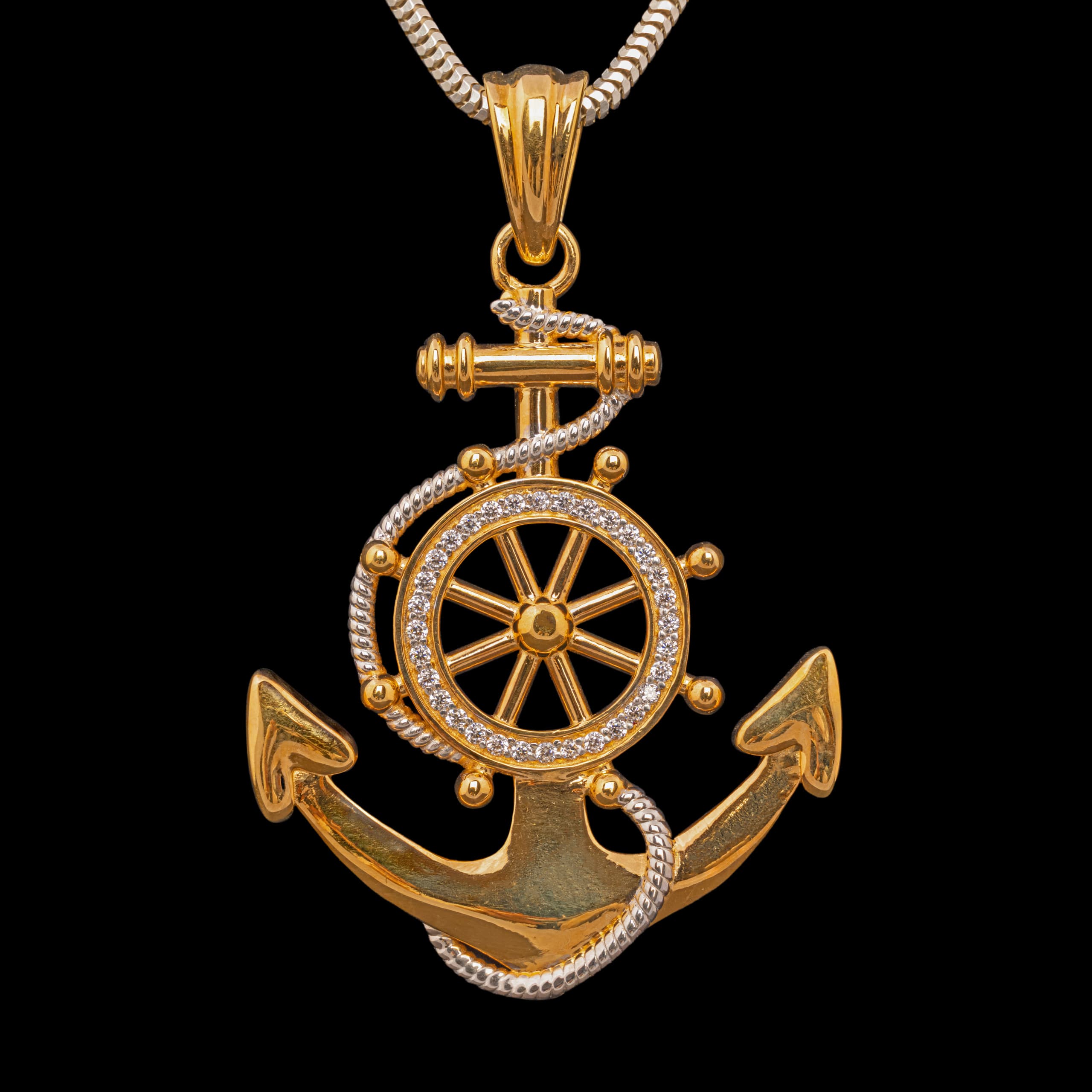 Gold anchor and ship's wheel pendant hanging from a snake chain